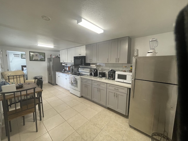 kitchen with white appliances, light tile patterned floors, gray cabinetry, a textured ceiling, and backsplash