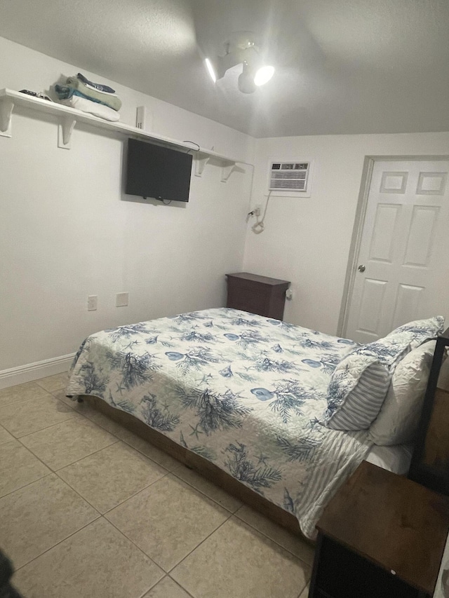 bedroom with light tile patterned floors, a ceiling fan, and a wall unit AC