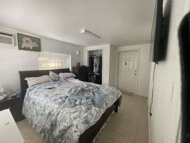 tiled bedroom with a textured ceiling and a closet