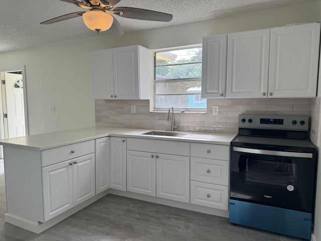 220 W Indies Rd, Tavernier, FL 33070 - kitchen with stainless steel electric range, a peninsula, a textured ceiling, white cabinets, and tasteful backsplash