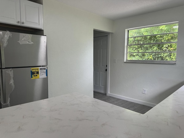 220 W Indies Rd, Tavernier, FL 33070 - kitchen with freestanding refrigerator, light stone counters, wood finished floors, and a textured wall