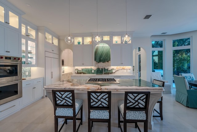 kitchen featuring pendant lighting, light stone counters, a center island, and appliances with stainless steel finishes