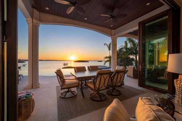 patio terrace at dusk with ceiling fan and a water view