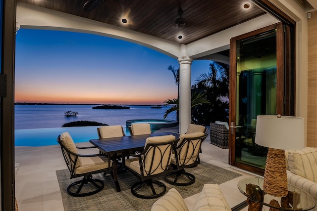 patio terrace at dusk featuring a water view