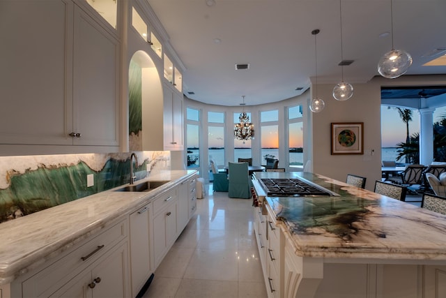 kitchen featuring white cabinetry, decorative light fixtures, a center island, and a water view