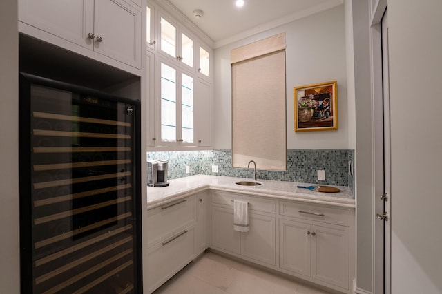 kitchen featuring sink, backsplash, wine cooler, ornamental molding, and white cabinets