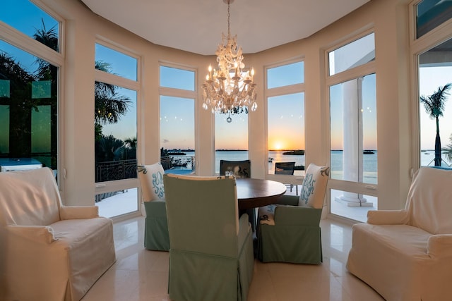 dining space with an inviting chandelier, light tile patterned flooring, and a water view