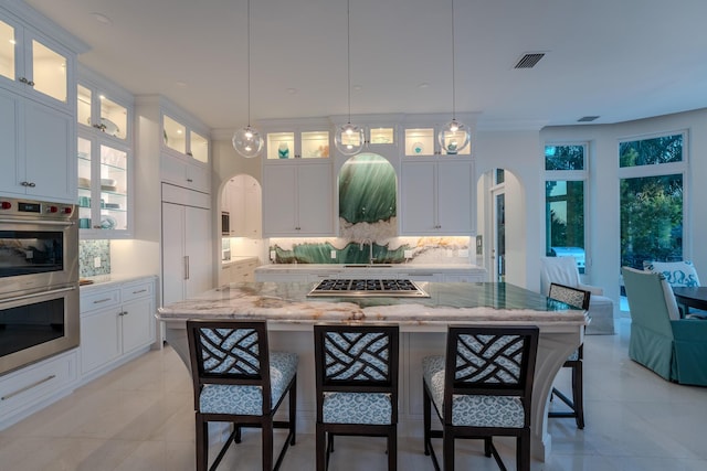 42 Cannon Royal Dr, Shark Key, FL 33040 - kitchen with arched walkways, stainless steel appliances, decorative backsplash, white cabinetry, and a breakfast bar