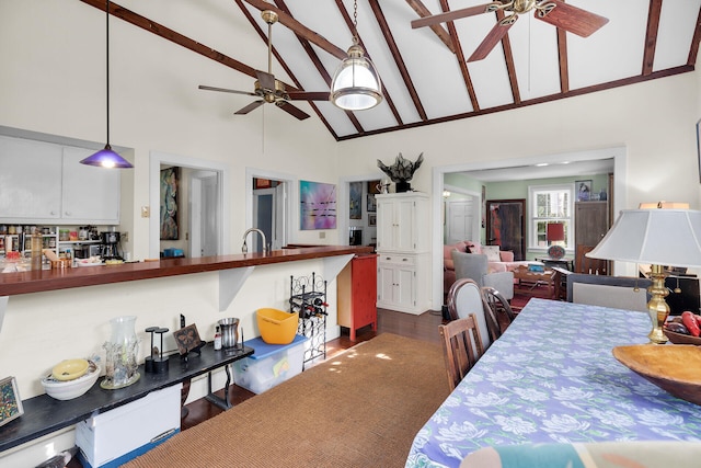 dining space featuring sink, ceiling fan, high vaulted ceiling, dark hardwood / wood-style floors, and beamed ceiling