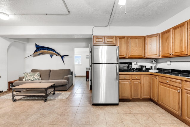 kitchen featuring light tile patterned floors, a textured ceiling, and stainless steel refrigerator