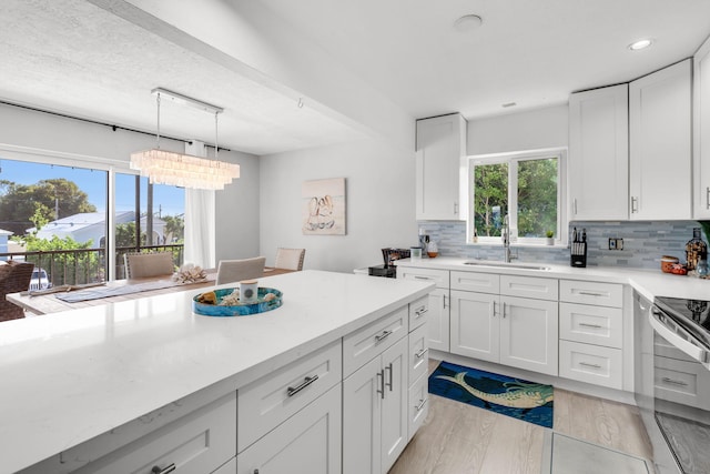 kitchen with stainless steel range with electric cooktop, sink, pendant lighting, and white cabinets