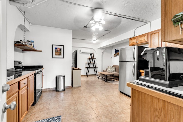 kitchen with stainless steel refrigerator, tile counters, ceiling fan, black range with electric stovetop, and a textured ceiling