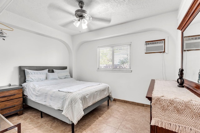 bedroom featuring ceiling fan, light tile patterned flooring, a textured ceiling, and a wall unit AC