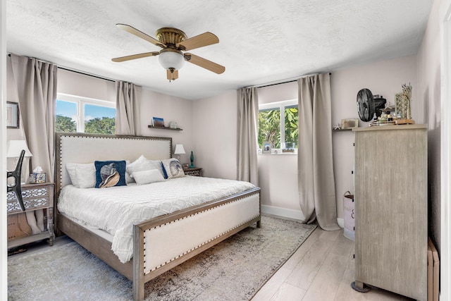 bedroom featuring ceiling fan, a textured ceiling, and light wood-type flooring