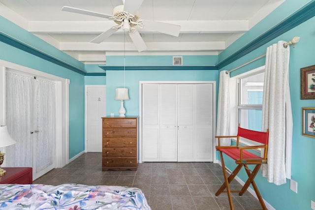 bedroom with ceiling fan, beam ceiling, a closet, and dark tile patterned floors