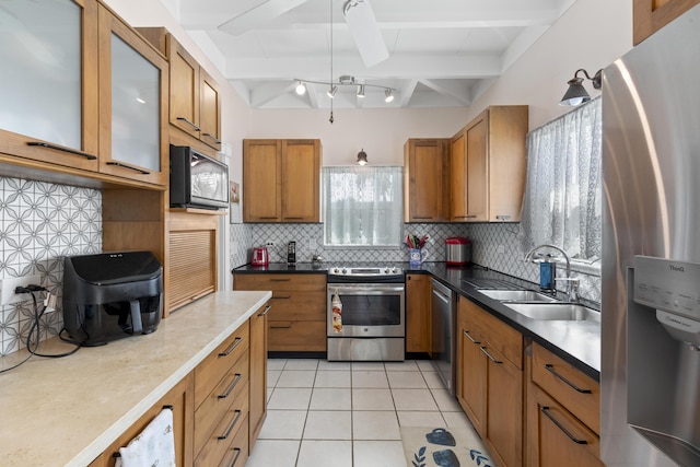 kitchen with sink, light tile patterned floors, beamed ceiling, stainless steel appliances, and decorative backsplash