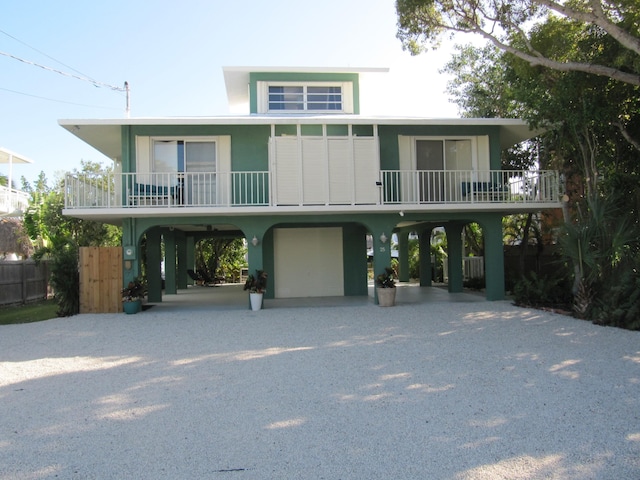 raised beach house featuring a garage, a balcony, and a carport