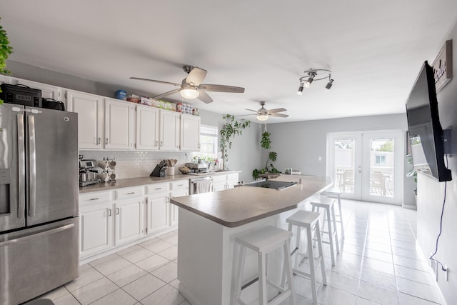 kitchen with white cabinetry, an island with sink, a kitchen breakfast bar, stainless steel appliances, and french doors