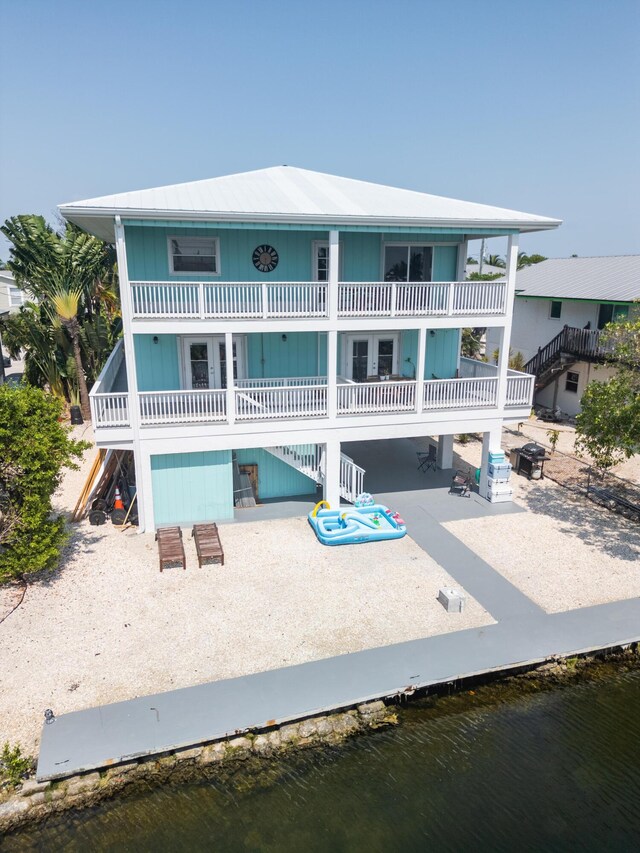 back of house with a patio, a balcony, and a water view