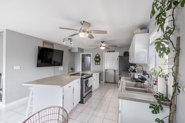 kitchen with sink, appliances with stainless steel finishes, white cabinetry, light tile patterned flooring, and kitchen peninsula