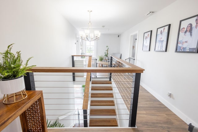 stairs with an inviting chandelier and hardwood / wood-style floors