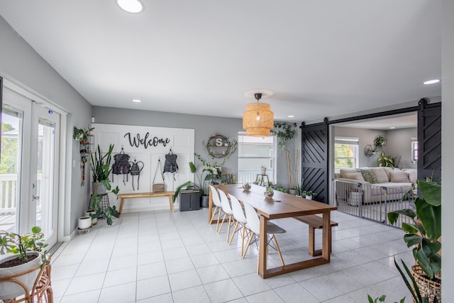 dining space with a barn door and light tile patterned floors