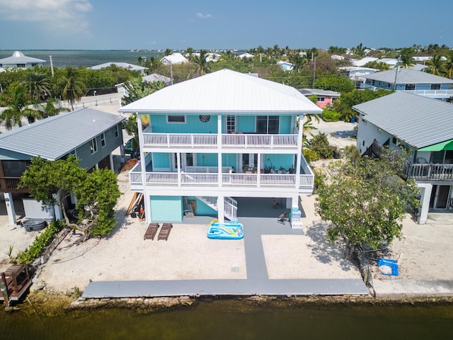 rear view of property with a balcony, a water view, and a patio area