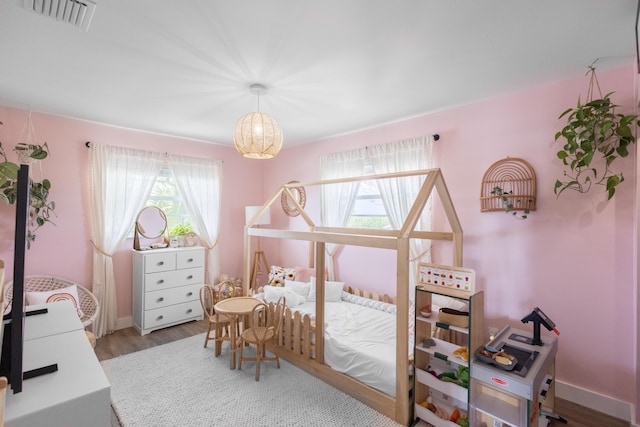 bedroom featuring hardwood / wood-style flooring and a chandelier