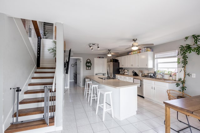 kitchen with white cabinetry, a kitchen bar, a center island, light tile patterned floors, and stainless steel appliances