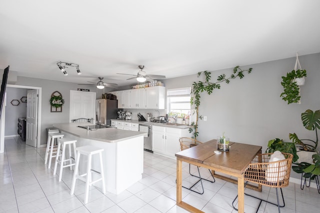 kitchen with appliances with stainless steel finishes, white cabinetry, a kitchen breakfast bar, light tile patterned flooring, and kitchen peninsula