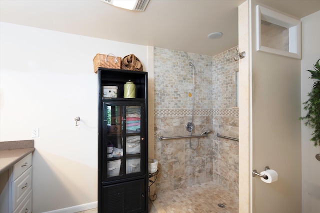 full bath with visible vents, a tile shower, and vanity