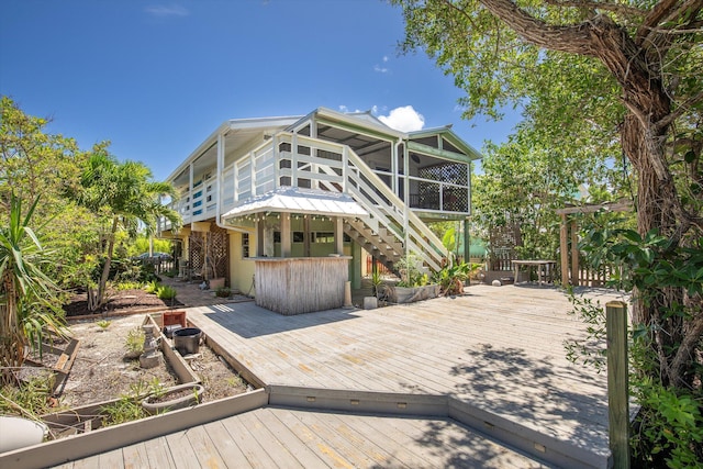 rear view of property with a deck, outdoor dry bar, stairs, and a sunroom