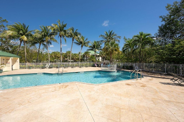 pool with a patio area and fence