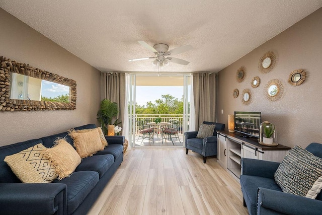 living room featuring light wood-type flooring, a textured ceiling, ceiling fan, and floor to ceiling windows