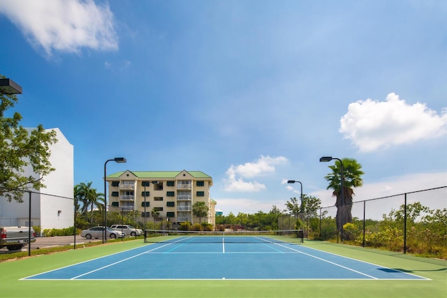 view of tennis court featuring community basketball court and fence