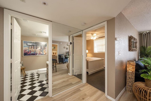 hall featuring light wood-style flooring and baseboards