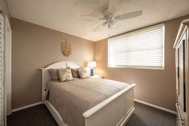 bedroom featuring baseboards, a textured ceiling, dark carpet, and a textured wall