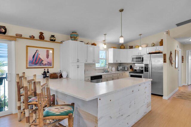 31135 Hollerich Dr, Big Pine, FL 33043 - kitchen with appliances with stainless steel finishes, a sink, a peninsula, light wood-style flooring, and backsplash