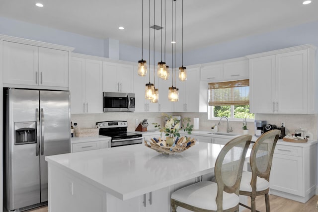 kitchen featuring white cabinetry, sink, hanging light fixtures, a center island, and stainless steel appliances