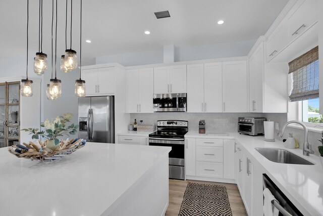 kitchen featuring sink, decorative light fixtures, white cabinets, and appliances with stainless steel finishes