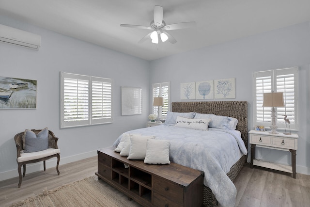 bedroom featuring an AC wall unit, ceiling fan, and light wood-type flooring