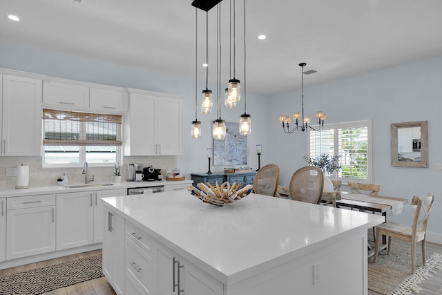 kitchen with pendant lighting, sink, white cabinets, and a kitchen island