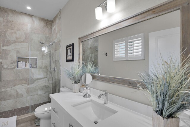 bathroom with vanity, toilet, and tiled shower