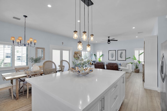 kitchen featuring white cabinetry, light hardwood / wood-style floors, a kitchen island, and pendant lighting