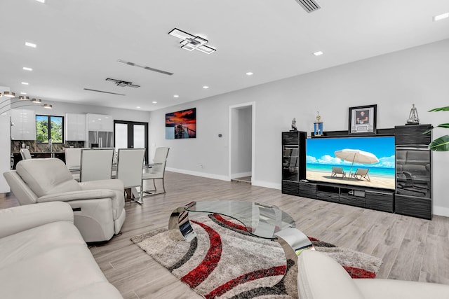 living area with light wood-style floors, recessed lighting, visible vents, and baseboards