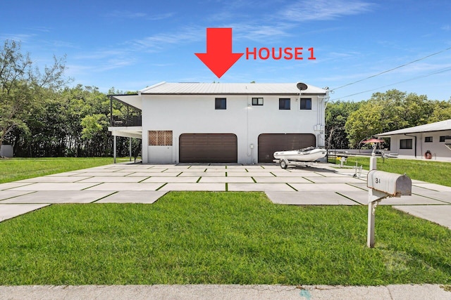 exterior space with driveway, stucco siding, a balcony, and a yard