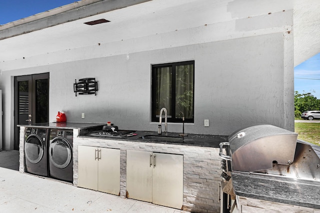 view of patio with an outdoor kitchen, independent washer and dryer, grilling area, and a sink