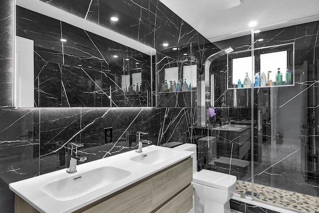 bathroom with a marble finish shower, a sink, tile walls, and toilet