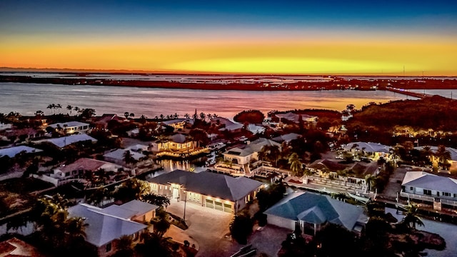 aerial view at dusk featuring a water view