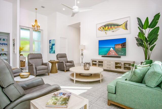 living room featuring ceiling fan with notable chandelier and a high ceiling